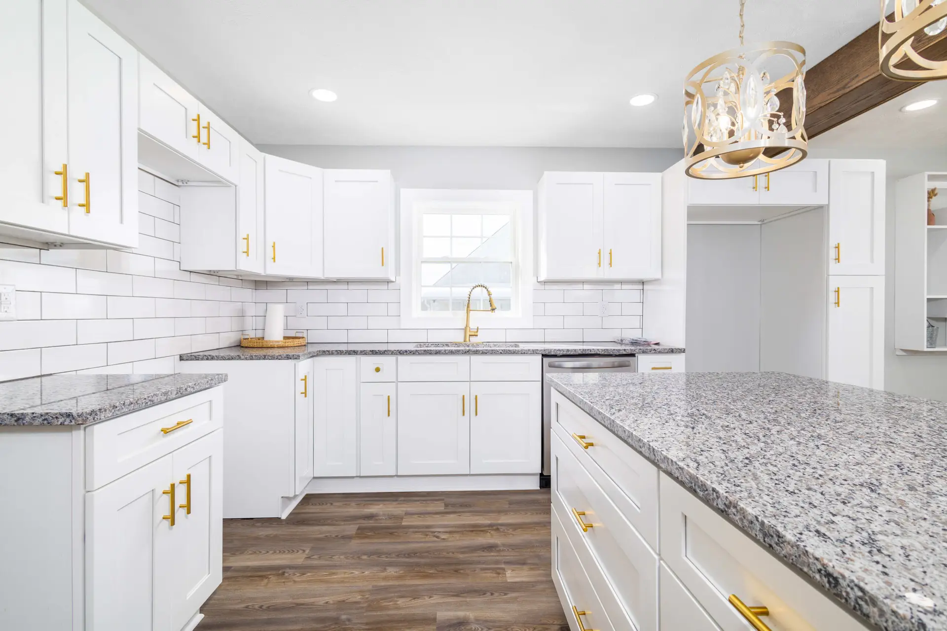 Renovated white kitchen with granite island by Steel Valley Contracting